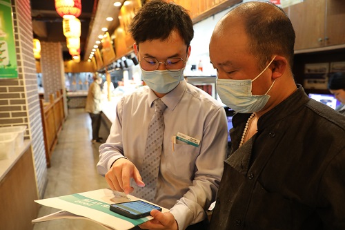 在金华市磊记小吃店内，农行客户经理指导店主通过掌银办理无还本续贷业务，解决小吃店的资金周转难题 (2).jpg